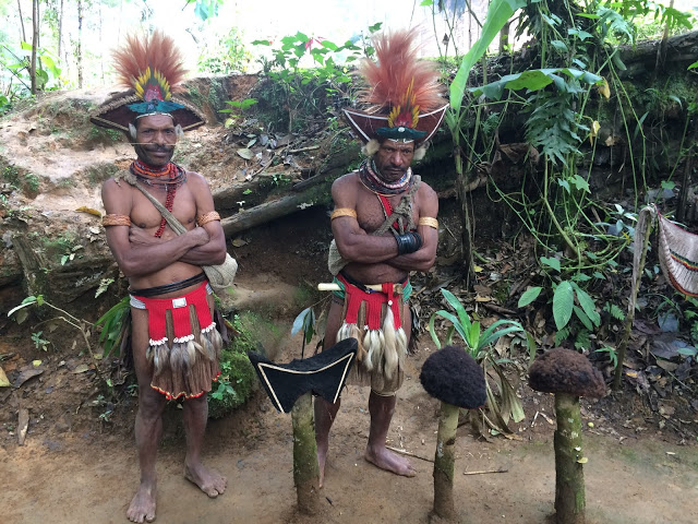 Huli tribesmen wear ceremonial wigs, with regular wigs on the two posts on the right