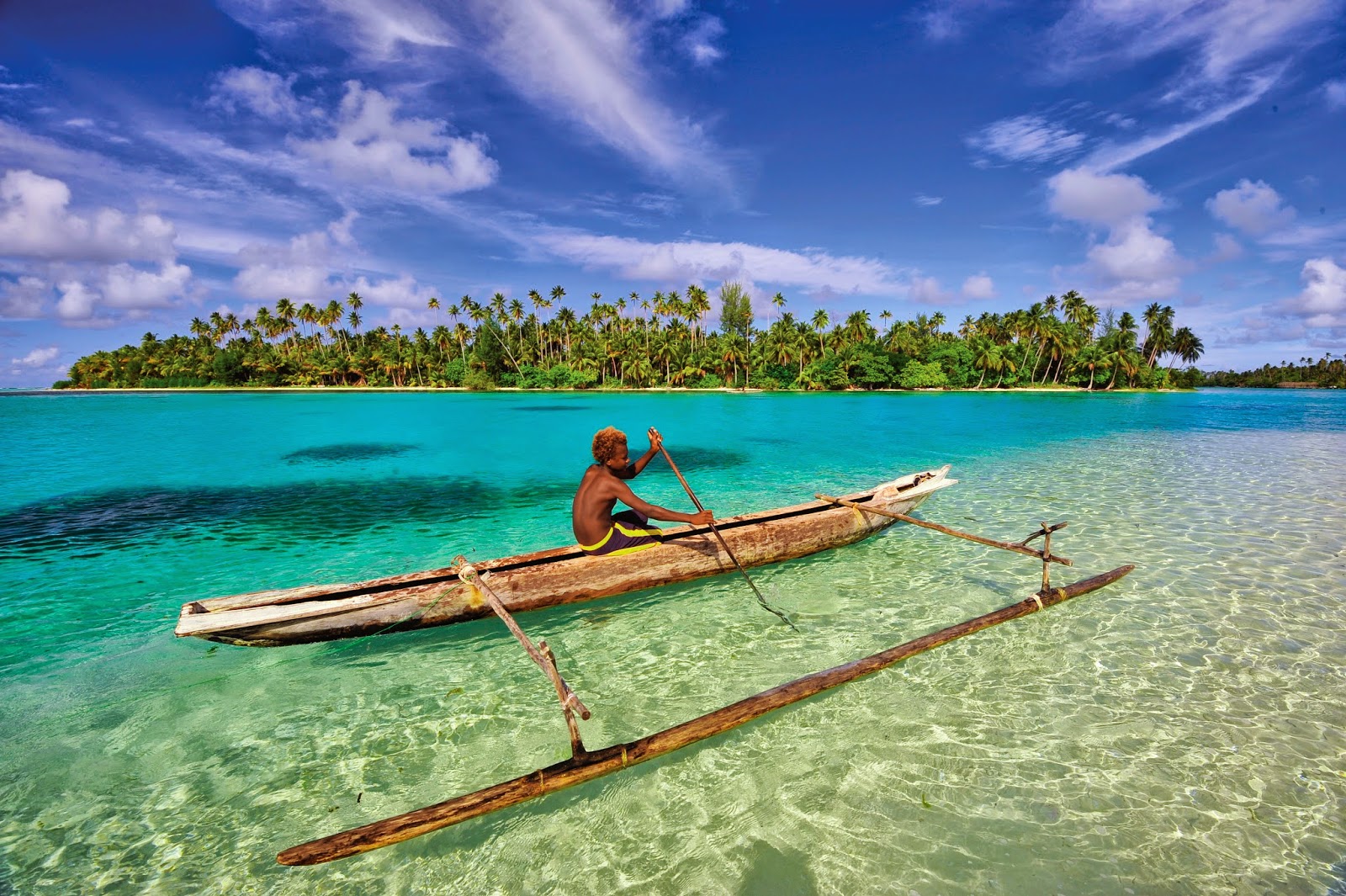 A boy canoeing in crystal clear water - Papua New Guinea